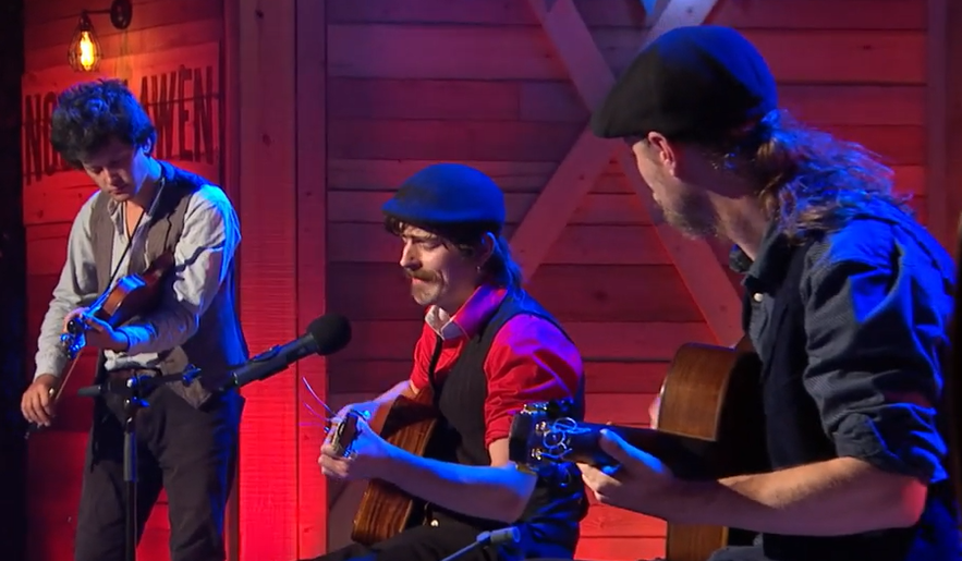 Three members of Tacla playing. One with fiddle, two on guitar